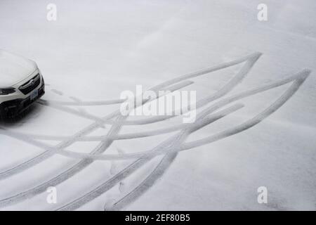 Autospuren und Spuren im Schnee auf einem Parkplatz in Lake Oswego, Oregon, am 12. Februar 2021, als eine leichte winterliche Mischung trifft die Portland Metro-Bereich gesehen. Stockfoto