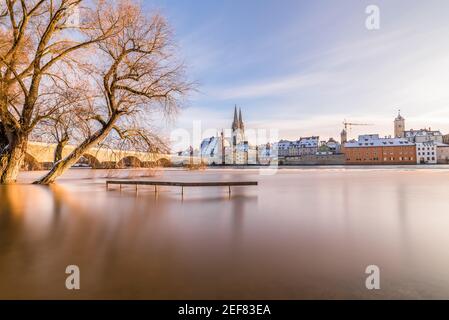 Donauflut im Winter 2021 in Regensburg mit Blick auf den Dom, die Altstadt und die überflutete Promenade und die Steinbrücke, Deutschland Stockfoto