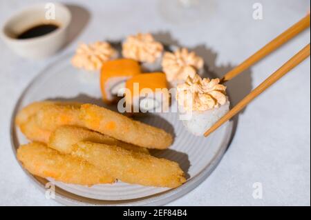 Sushi-Brötchen mit Lachs, Käsecreme und gebratenen Garnelen auf grauem Teller Stockfoto