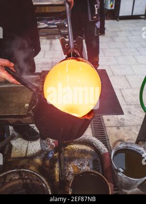 Mann Künstler Hände arbeiten an einem Blasglas Stück. Formglas Schüssel mit nassem Werkzeug. Runden des heißen Glases Stockfoto