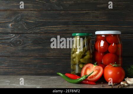 Gläser mit eingelegten Tomaten und Gurken auf Holzgrund Stockfoto