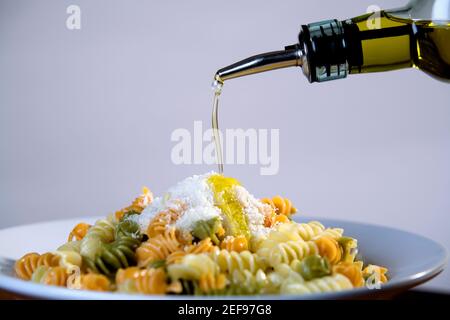 Olivenöl wird auf einen Teller Nudeln gegossen Stockfoto