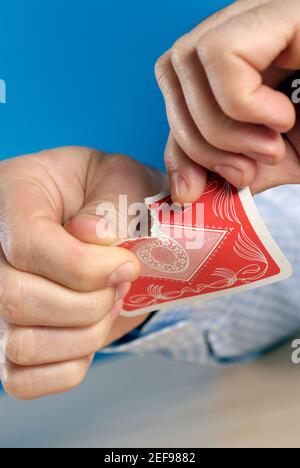 Nahaufnahme einer personÅ½s Hände, die eine Karte zerreißen Stockfoto