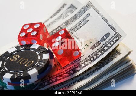 Zwei Würfel mit einem Spielchip auf einem Stapel von US-Dollar-Scheine Stockfoto