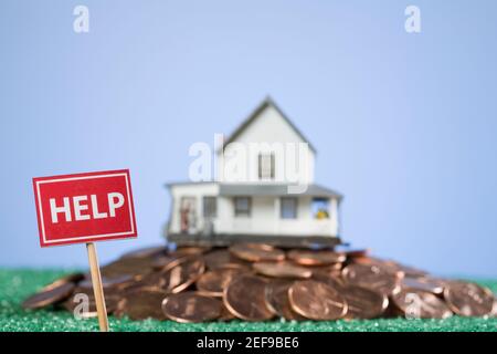 Hilfe Schild vor einem Modell zu Hause auf Ein Haufen Münzen Stockfoto