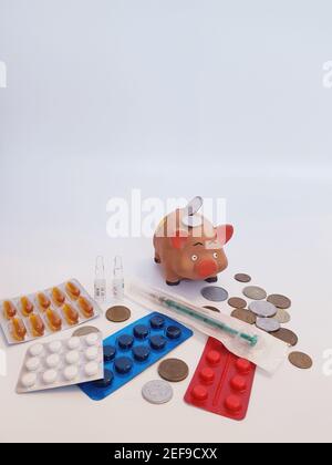 Sparschwein mit Geld, Pillen, Medikamenten, Spritze, Ampullen auf weißem Hintergrund. Behandlungskosten. Gewinne bei Arzneimitteln. Stockfoto