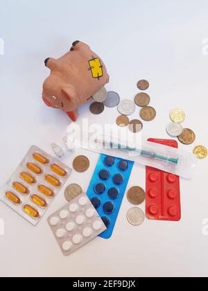 Sparschwein mit Geld, Pillen, Medikamenten, Spritze, Ampullen auf weißem Hintergrund. Behandlungskosten. Stockfoto