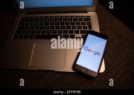 Smartphone mit Google-Logo auf der Tastatur eines Laptops ruht. Google ist die am häufigsten verwendete Suchmaschine im World Wide Web. Stockfoto