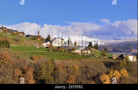 Blick auf alpines Dorf in einem Hügel und verschneiten Berg Hintergrund Stockfoto