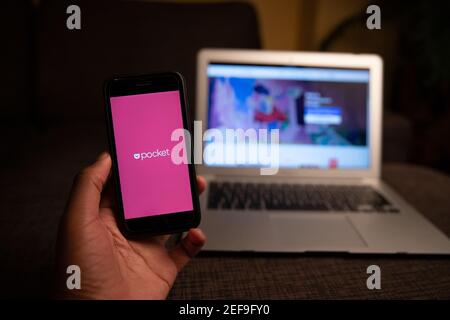 Das Pocket App-Logo auf dem Bildschirm eines Smartphones, das auf einem Laptop ruht, ist ein Social Bookmarking-Dienst zum Speichern, Teilen und Entdecken von Weblesezeichen Stockfoto