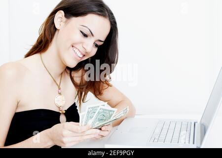 Nahaufnahme einer jungen Frau, die vor dem Hotel Dollarscheine zählt Eines Laptops Stockfoto