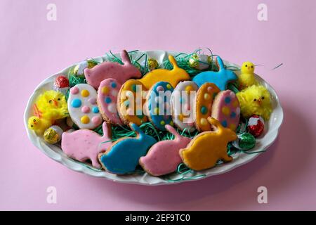 Kekse für den Osterurlaub auf einem Teller dekoriert. Hausgemachte Kekse in Form von Kaninchen und bunten Eiern Stockfoto
