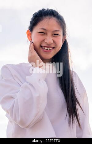 Junge asiatische Frau in weiß gekleidet lachen glücklich und lustig, Konzept der Jugend und gesunden Lebensstil Stockfoto