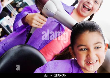 Nahaufnahme eines Mädchens, das einen Fön auf ihr verwendet Schwester Stockfoto