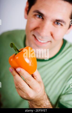 Porträt eines mittleren Erwachsenen mit einer orangefarbenen Glocke Pfeffer und Lächeln Stockfoto