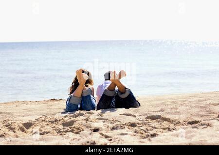 Rückansicht eines mittelerwachsenen Mannes und eines Jungen Frau liegt am Strand Stockfoto