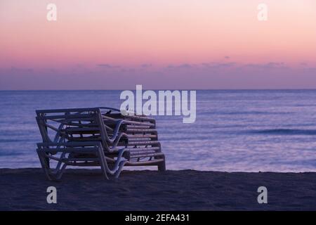 Stapel von gefalteten Liegestühlen am Strand, South Beach, Miami, Florida, USA Stockfoto