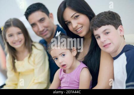 Porträt von drei Kindern, die mit ihren Eltern zusammen sitzen Stockfoto