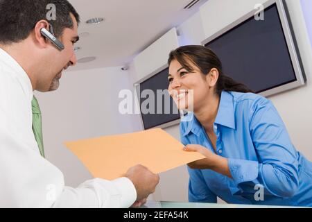 Empfangsdame gibt einem Geschäftsmann eine Akte Stockfoto