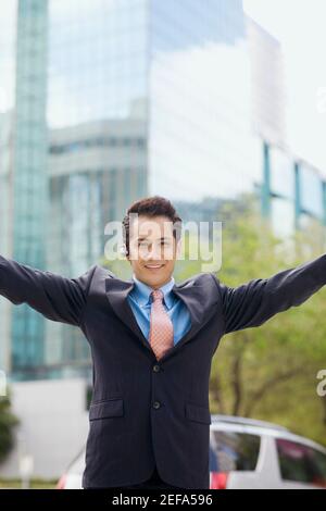 Porträt eines Geschäftsmannes stehend mit ausgestreckten Armen und Lächelnd Stockfoto