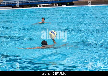 Zwei junge Männer spielen Wasserball in einem Schwimmbad Stockfoto