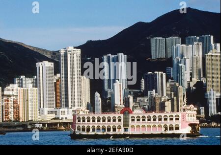 Fähre im Meer vor Wolkenkratzern, Hongkong, China Stockfoto