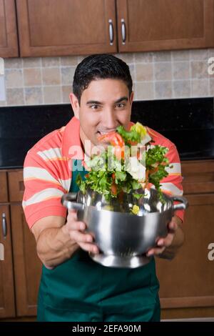 Mittelalter Mann, der Salat in einem Sieb mischt Stockfoto