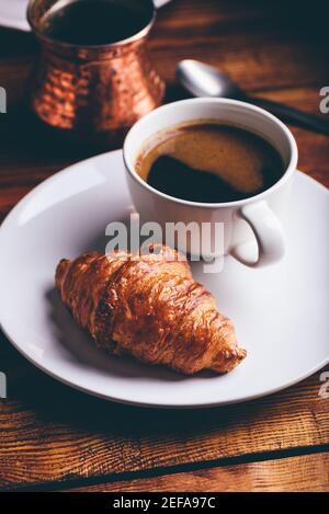 Tasse schwarzen Kaffee und frischen Croissant auf Holztisch Stockfoto