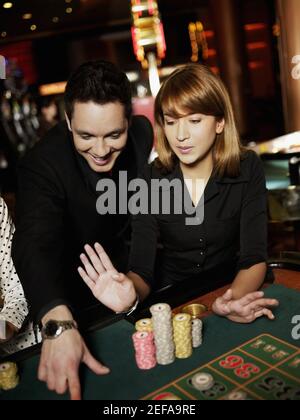 Mittlerer Erwachsener Mann und eine junge Frau spielen in einem kasino Stockfoto