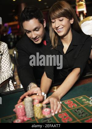 Mittelerwachsener Mann mit einer jungen Frau, die Spielchips platziert Auf einem Spieltisch Stockfoto