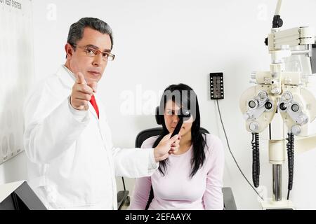Porträt eines männlichen Arztes, der womanÅ½s Auge eines jungen Mannes untersucht Stockfoto