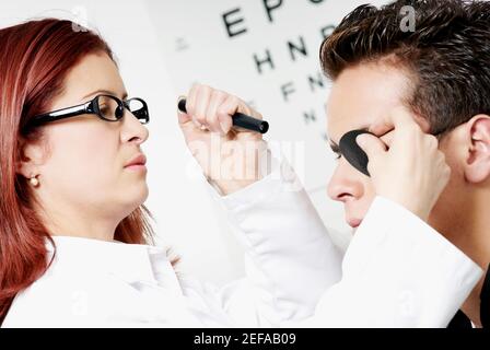 Nahaufnahme einer weiblichen Optometristin, die die Augen eines Jungen untersucht Mann Stockfoto