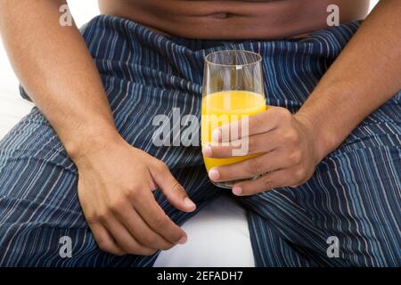 Mittelansicht eines jungen Mannes, der ein Glas hält Orangensaft Stockfoto