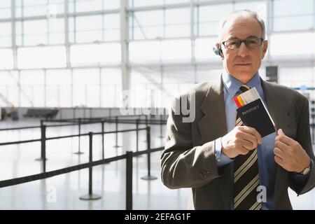 Porträt eines Geschäftsmannes, der einen Pass mit einem Flugzeug legt Ticket in seiner coatÅ½s Tasche Stockfoto