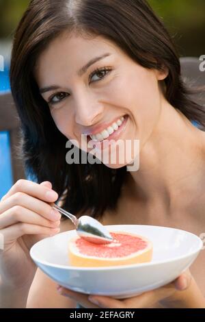 Porträt einer jungen Frau, die Grapefruit isst und lächelt Stockfoto