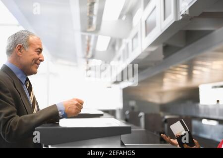 Seitenprofil eines Geschäftsmannes, der an einem Kassenschalter steht In einem Flughafen Stockfoto