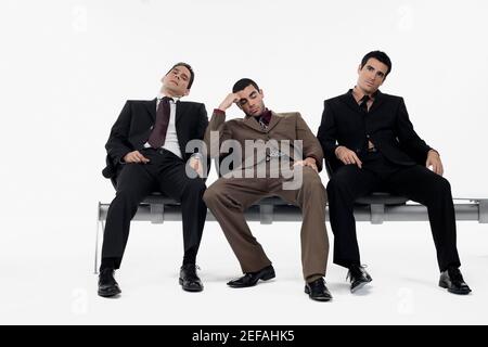 Drei Geschäftsleute sitzen auf einer Bank und schauen gestresst Stockfoto