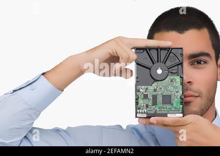 Porträt eines Geschäftsmannes, der eine Festplatte vor sich hält Seines Gesichts Stockfoto