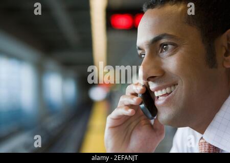 Nahaufnahme eines Geschäftsmannes, der mit einem Mobiltelefon spricht Eine U-Bahn-Station Stockfoto