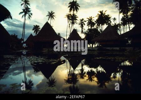 Spiegelung von Hütten und Bäumen im Wasser, Huahine Insel, Französisch Polynesien Stockfoto