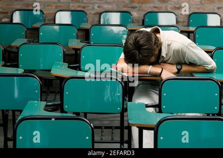 Junger Mann, der in einem Klassenzimmer nippt Stockfoto