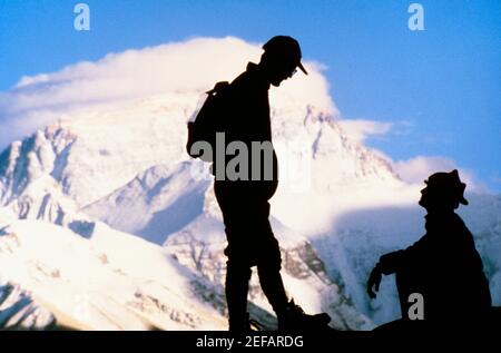 Silhouette von zwei Männern auf einem Berg mit schneebedeckten Bergen im Hintergrund, Mt. Everest, Tibet, China Stockfoto