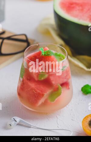 Ein Glas frischer Wassermelone-Cocktail mit Gin und Soda, garniert mit Minzblättern auf hellem Betongrund Stockfoto