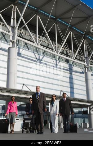 Drei Geschäftsleute mit zwei Geschäftsfrauen draußen auf einem Flughafen Stockfoto
