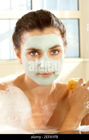 Porträt einer jungen Frau, die sich mit einem Schwamm schrubbt Stockfoto
