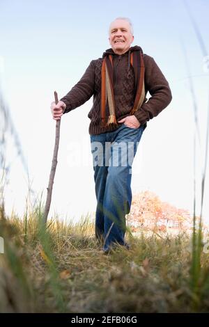 Älterer Mann, der auf einem Feld wandert Stockfoto