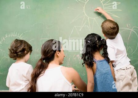 Rückansicht einer Lehrerin, die ihre Schüler unterrichtet Stockfoto