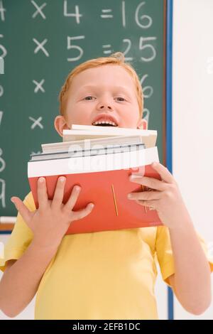 Porträt eines Schuljungen mit einem Stapel von Büchern und Lächelnd Stockfoto