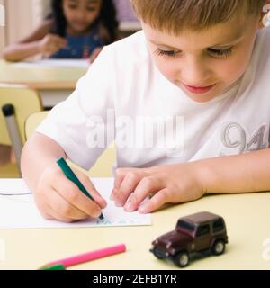 Nahaufnahme eines Jungen, der auf einem Blatt Papier zeichnet Stockfoto