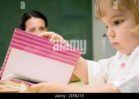 Seitenprofil eines Jungen, der mit ihm ein Buch liest Lehrer, der neben ihm sitzt Stockfoto